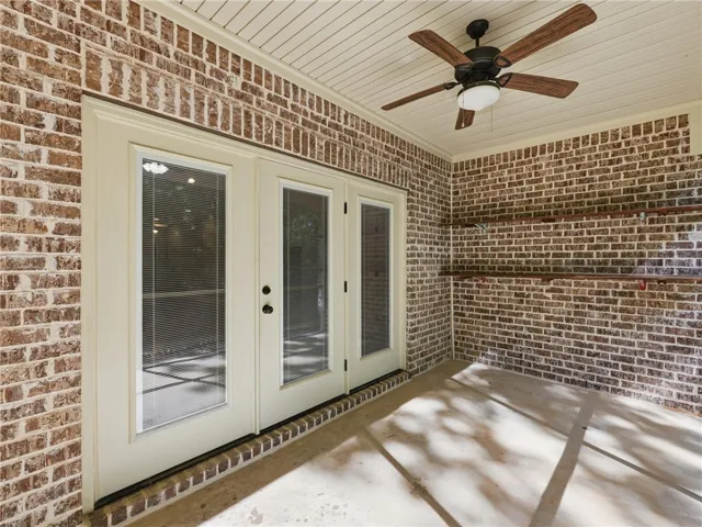 This inviting covered patio features elegant French doors and durable brick construction, perfect for outdoor enjoyment.