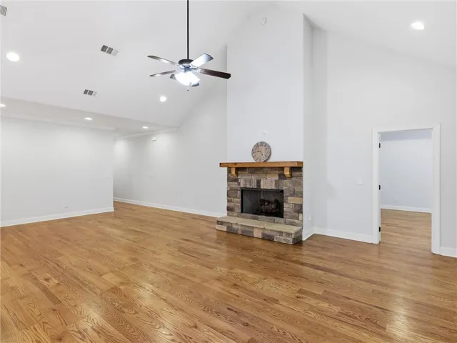 This expansive living area features a grand stone fireplace, soaring vaulted ceilings, and rich hardwood flooring.