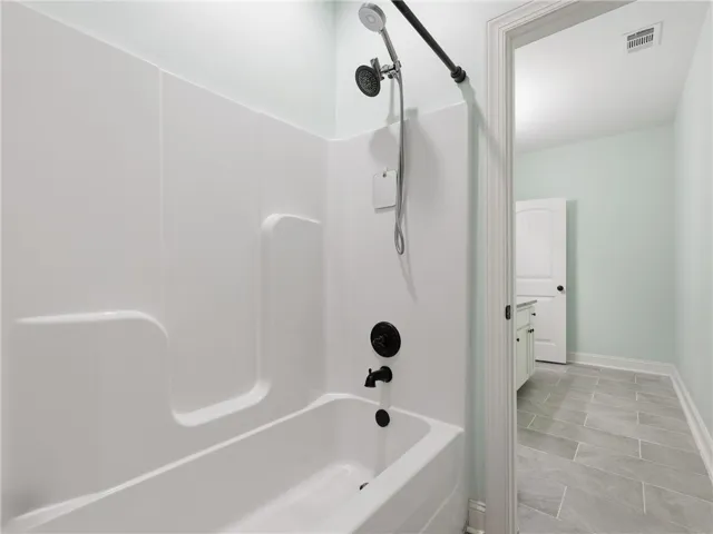 This clean bathroom features a tub-shower combination, modern fixtures, and durable tile flooring.