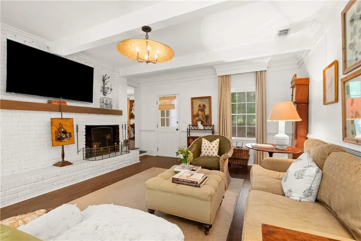 This inviting living space features a cozy fireplace, elegant crown molding, and rich hardwood flooring.