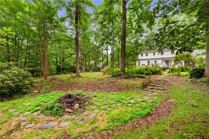 This tranquil yard features a beautiful stone pathway leading to a charming white residence.