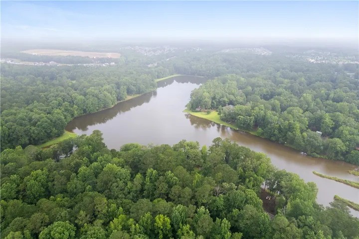 This aerial view showcases a serene lake surrounded by lush green forests.