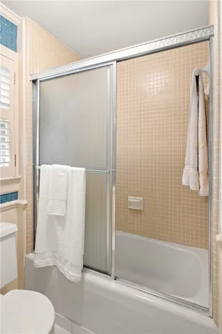 This bathroom features a bathtub with a shower and tile walls.