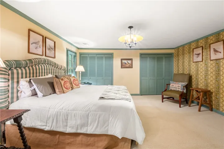 This inviting bedroom features soft carpeting, louvered closet doors, and crown molding for classic comfort.