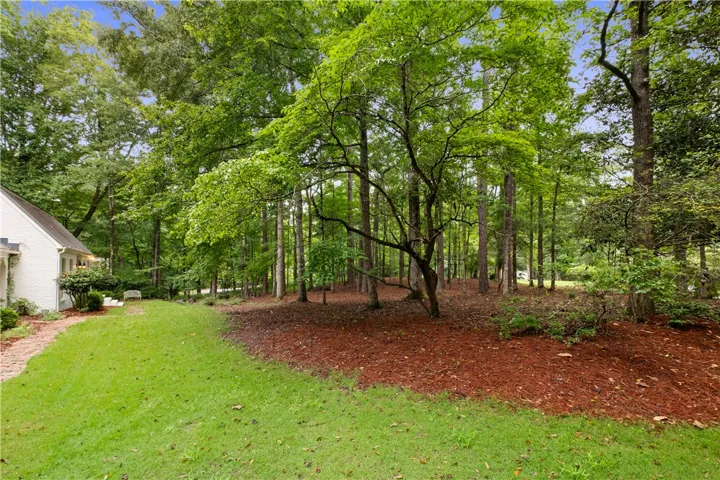 This tranquil yard features lush greenery, a winding brick path, and mature trees for ultimate privacy.