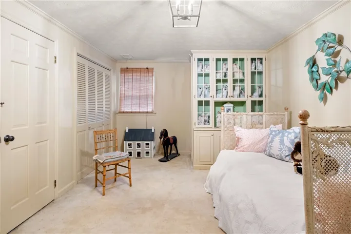 This cozy bedroom features plush carpeting and a large window, creating a serene and comfortable retreat.