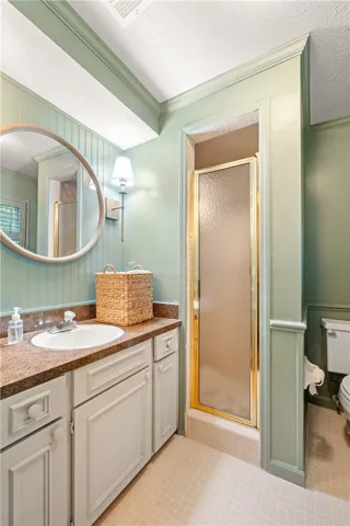 This bathroom features a sleek vanity, a convenient shower, and charming wainscoting.