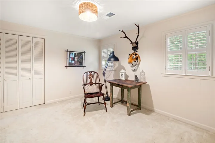 This cozy room offers natural light, carpeted flooring, and a closet with louvered doors.