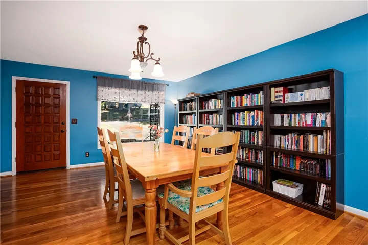 This dining area features rich wood flooring, a window offering natural light, and ample built-in shelving.
