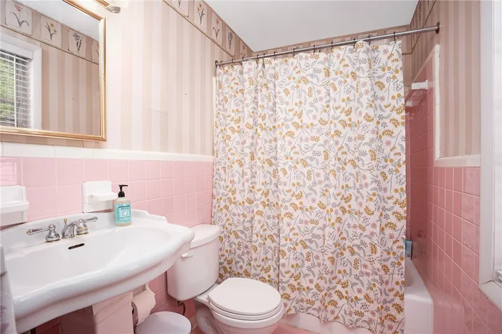 This full bathroom offers vibrant tilework and a convenient window.
