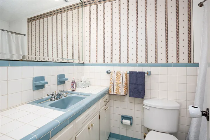 This bathroom features classic tile work and a functional vanity, offering a vintage charm.