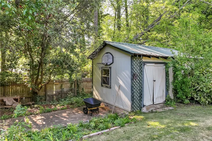 This outdoor shed offers practical storage solutions amidst lush surroundings and a fenced yard.