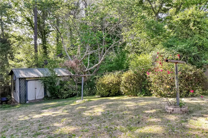 Enjoy the expansive yard featuring mature trees and practical outdoor storage.