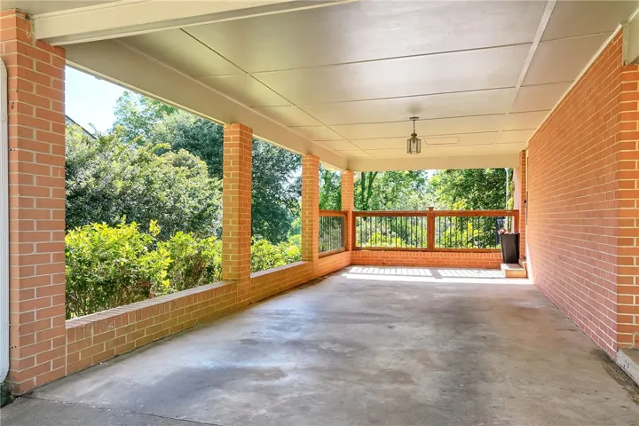 This covered patio offers a serene outdoor retreat with brick accents and lush natural surroundings.