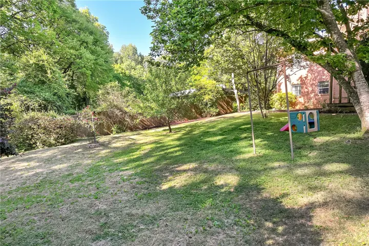 This spacious backyard offers ample green space and natural surroundings for relaxation and recreation.