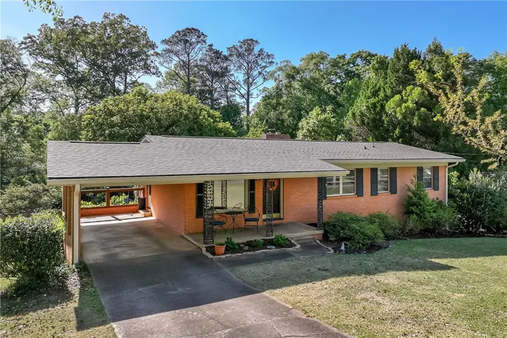 This charming brick ranch offers a welcoming facade with a covered carport and lush landscaping.