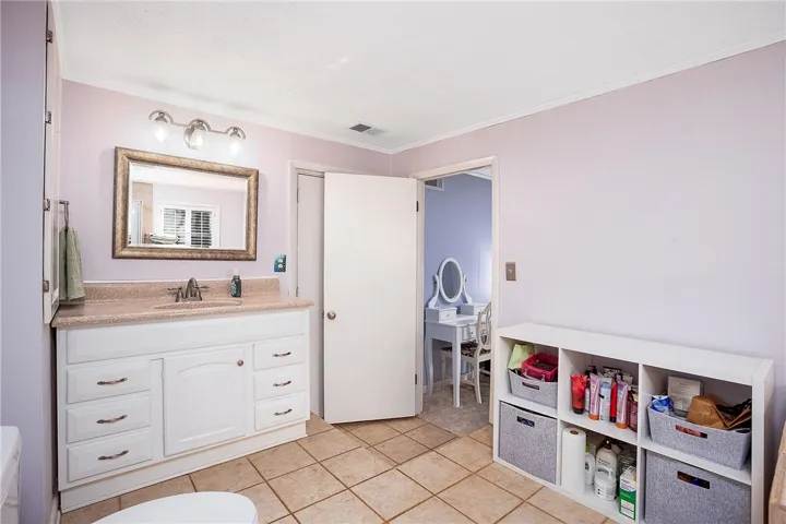 This bathroom features a single vanity, a large mirror, and tiled flooring for a functional space.
