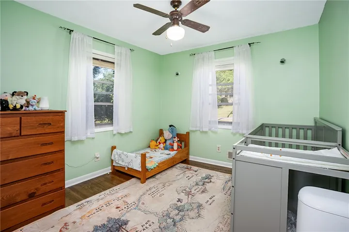 This cozy room features durable hardwood flooring and a ceiling fan, offering comfort and charm.