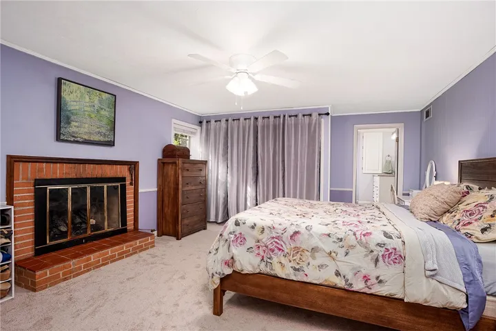 This cozy bedroom offers a warm retreat, featuring a classic brick fireplace and soft carpeting.