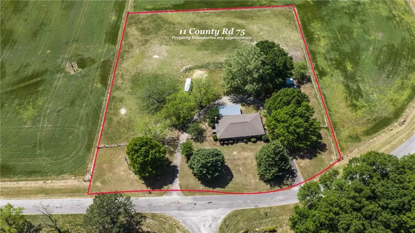 Aerial view of a sprawling property with a single-family home and expansive green space.