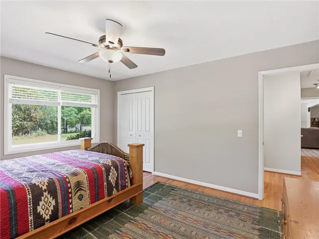 This inviting bedroom features natural hardwood flooring, a bright window, and convenient bi-fold closet doors.