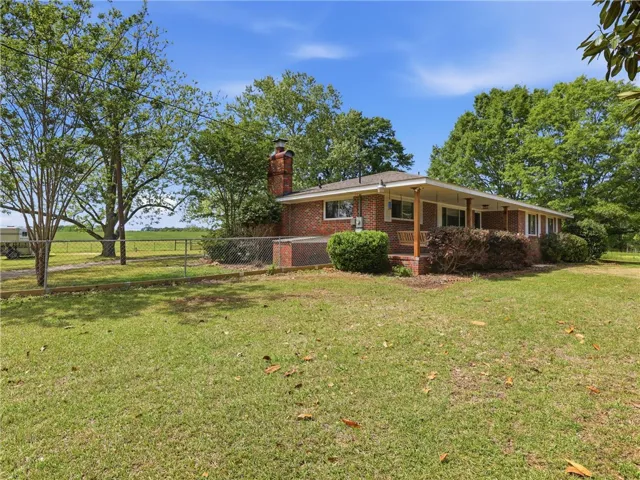 This classic brick residence features a welcoming porch, lush lawn, and ample outdoor space.