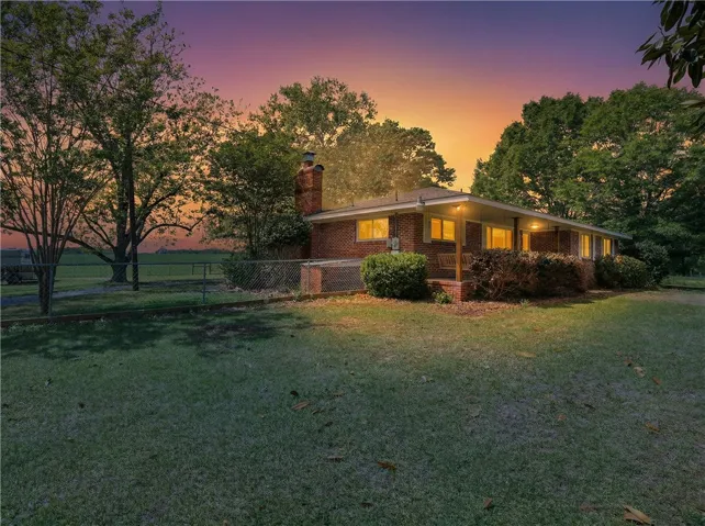 This charming brick home features a spacious yard and inviting covered porch.  Photo is AI generated.