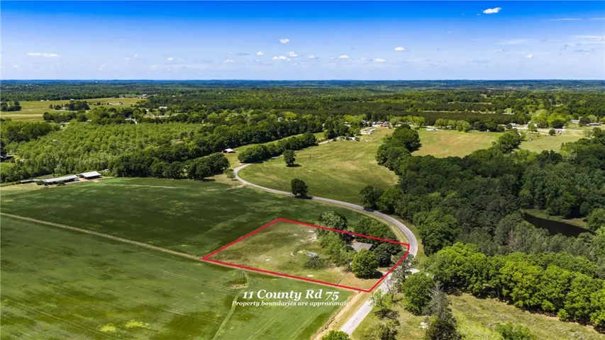 Expansive rural landscape with lush fields and winding roads under a vast sky.