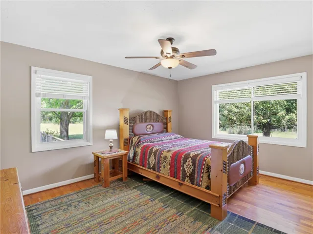 This spacious bedroom features warm hardwood floors and abundant natural light through multiple windows.