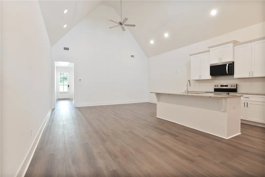 Living, dining, and kitchen, featuring tall vaulted ceiling running the length of the room