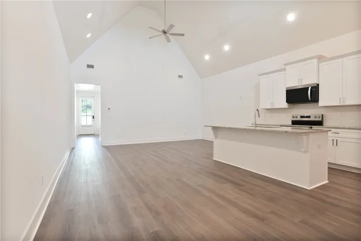 Living, dining, and kitchen, featuring tall vaulted ceiling running the length of the room