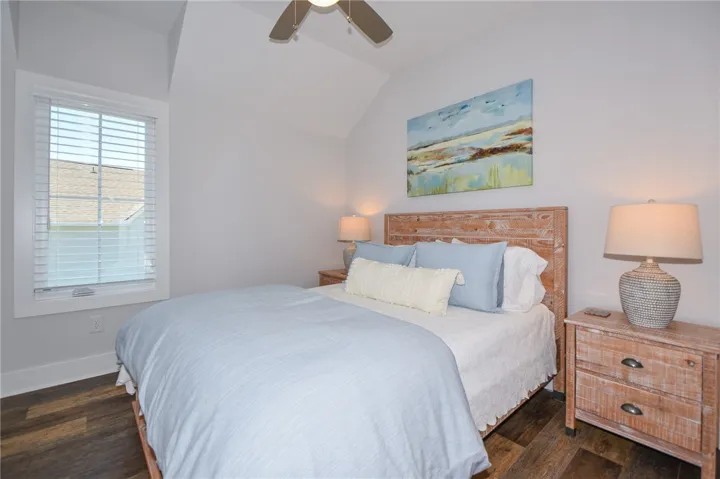 This tranquil bedroom features rich wood flooring and vaulted ceilings, creating a serene and spacious retreat.