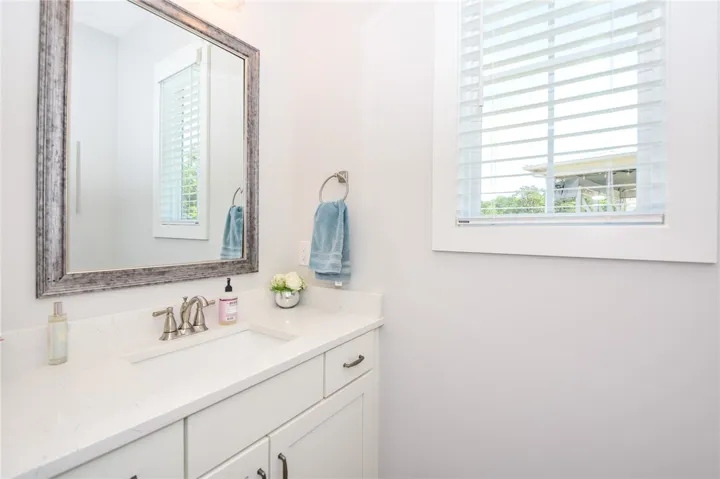 This bright bathroom features a vanity with granite counters and a window with natural light.