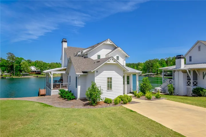 This charming lakeside dwelling features crisp white siding and inviting outdoor spaces perfect for enjoying waterfront living.