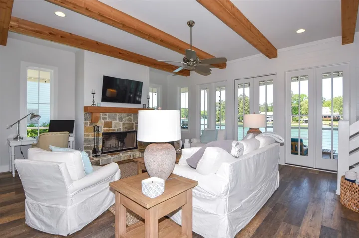 This living room features exposed beams, a stone fireplace, and French doors that open to scenic views.