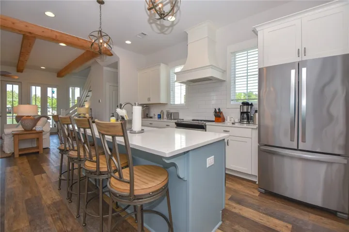 This open concept kitchen features warm wood flooring and beams, offering both style and functionality.