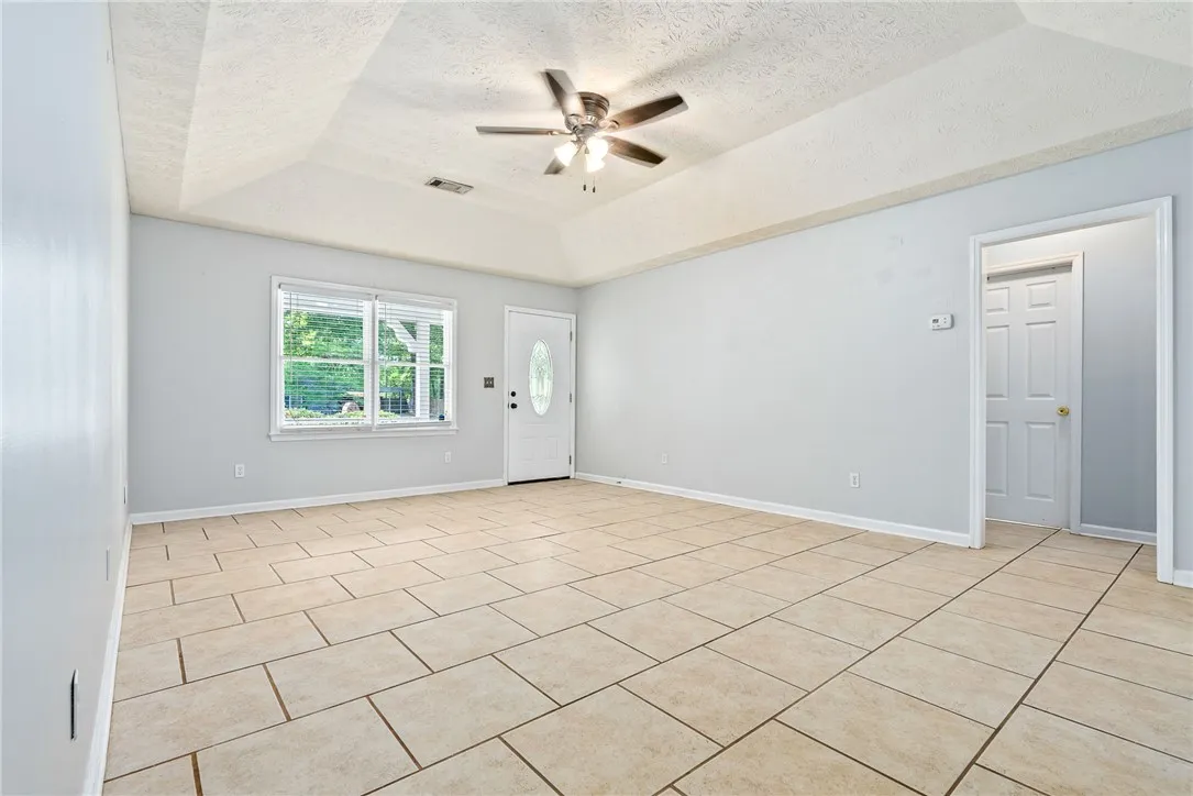Living Area - This airy living space features ample natural light, a ceiling fan, and durable tile flooring.