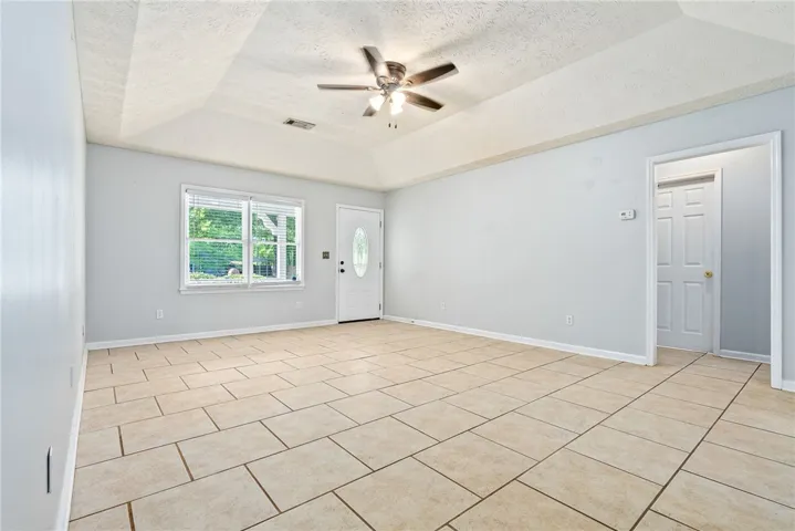 Living Area - This airy living space features ample natural light, a ceiling fan, and durable tile flooring.