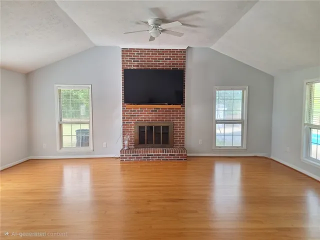 Bright and airy living area featuring a prominent brick fireplace and gleaming hardwood floors.