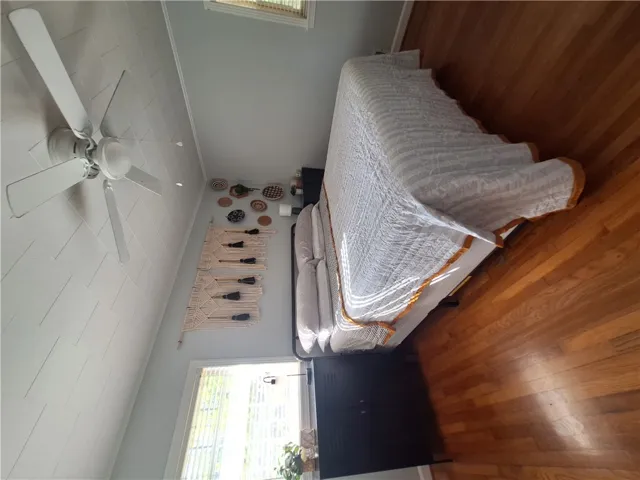 This spacious bedroom offers high ceilings and rich hardwood flooring for comfortable living.