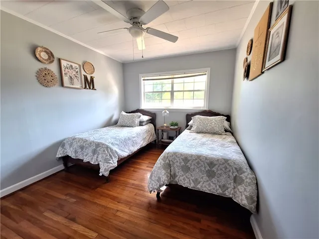 This serene bedroom offers a bright window and rich hardwood flooring.