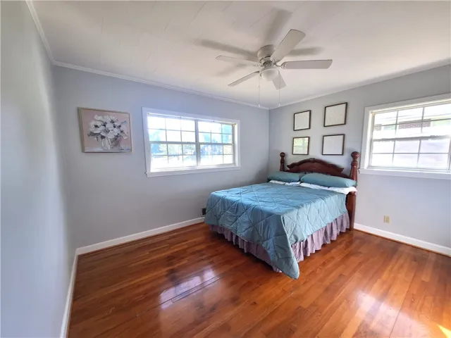 This inviting bedroom features rich hardwood flooring and abundant natural light.