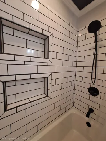 This bathroom features pristine subway tile and integrated shower niches, offering both style and functionality.