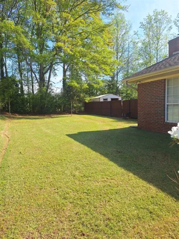 This spacious yard offers a serene setting with mature trees and a fenced boundary.