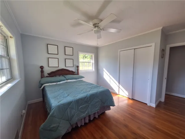This spacious bedroom features ample natural light and beautiful hardwood flooring.