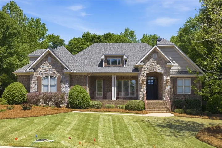 This charming home offers a welcoming facade with a mix of brick and stone, set amidst mature landscaping.