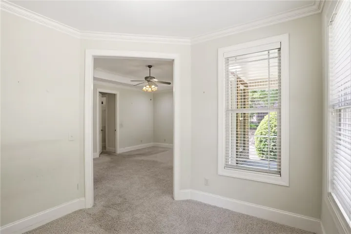 This bright room features elegant crown molding and soft carpeting, creating a welcoming and comfortable atmosphere.