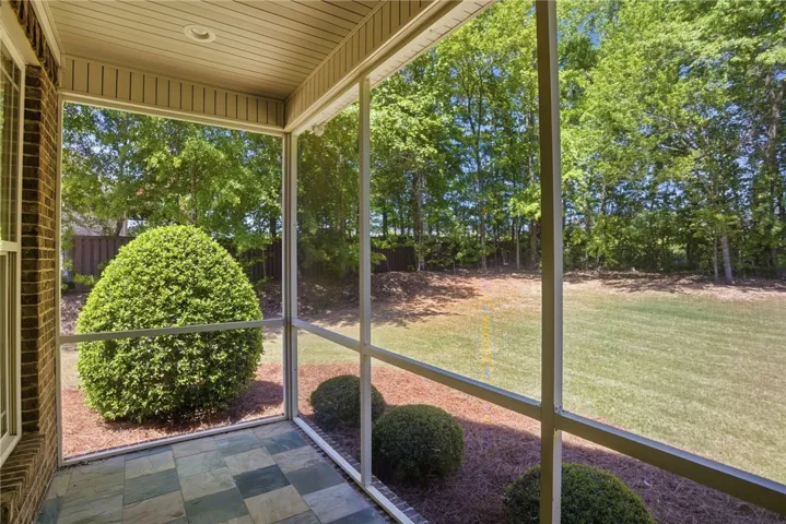 This inviting screened porch offers serene views of the expansive private yard.