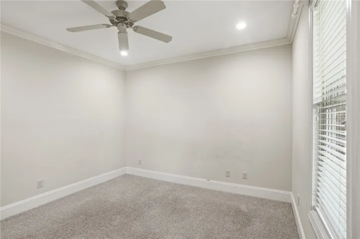 This spacious room features elegant crown molding and soft carpeting, creating a comfortable and inviting atmosphere.