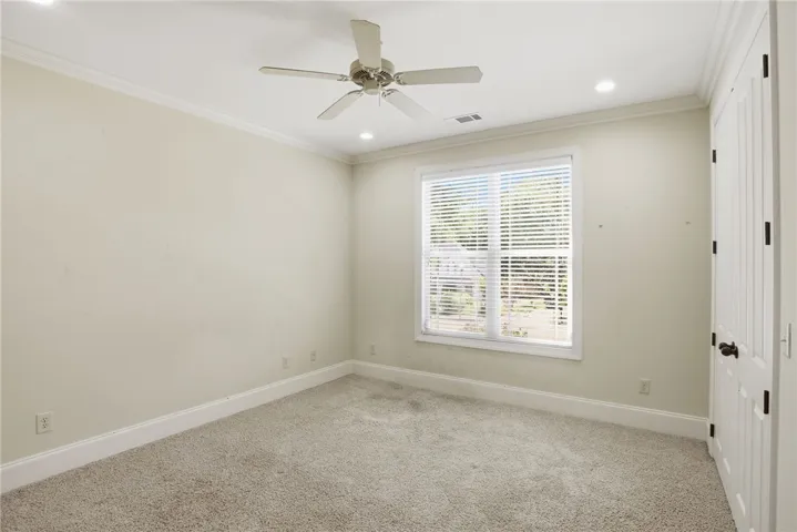 This bright room features a large window, crown molding, and plush carpet, perfect for a peaceful retreat.